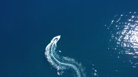 on a sunny day, a motor boat is seen traveling through the sea in a top-down tracking shot