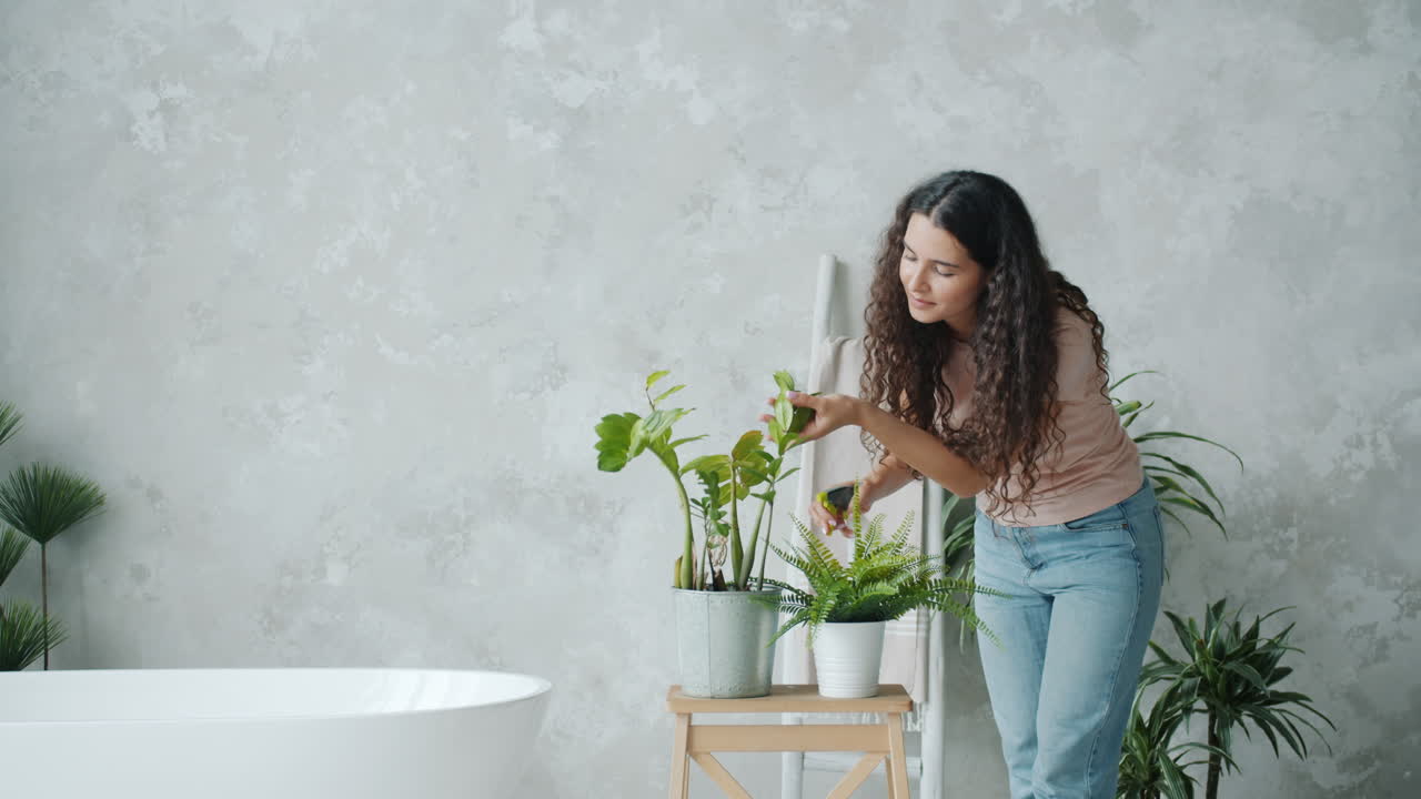 Woman watering houseplants in a bathroom