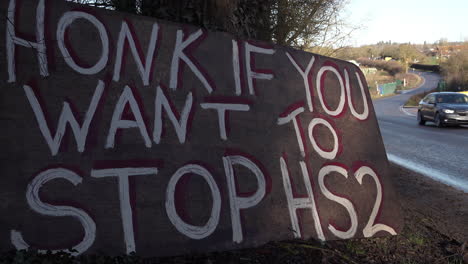 vehicles pass protest signs by the side of the road opposing the hs2 train line construction