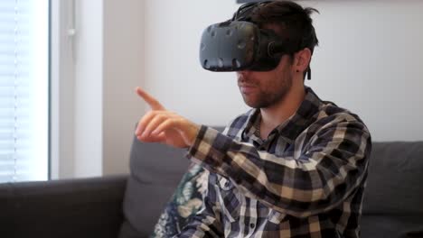 Eine-Mittlere-Aufnahme-Eines-Weißen-Jungen-Mannes,-Der-Virtual-Reality-Spielt,-Während-Er-Auf-Einer-Couch-Ohne-Controller-Sitzt