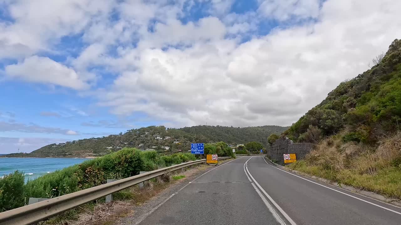 A 15-second video capturing a drive along the Great Ocean Road, showcasing coastal views, winding roads, and lush greenery under a partly cloudy sky