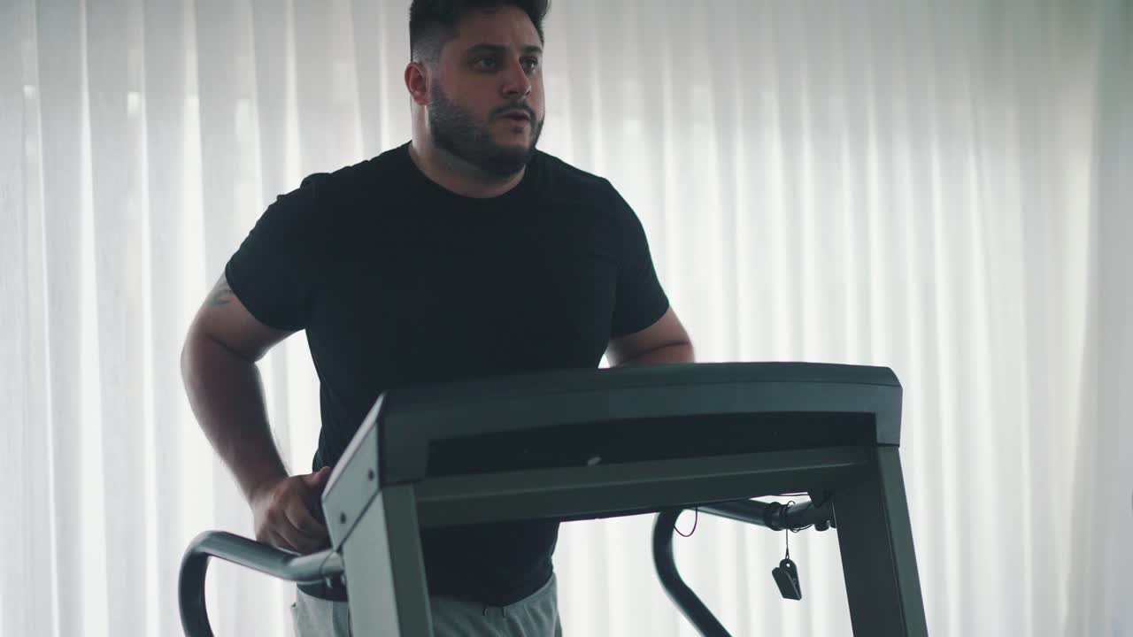 Young bearded man training on treadmill machine workout in the gym slow motion movement around