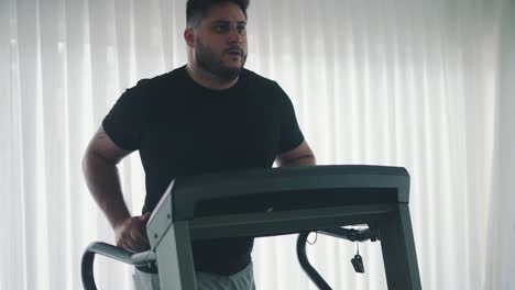 Young-bearded-man-training-on-treadmill-machine-workout-in-the-gym-slow-motion-movement-around