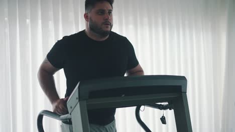 young bearded man training on treadmill machine workout in the gym slow motion movement around