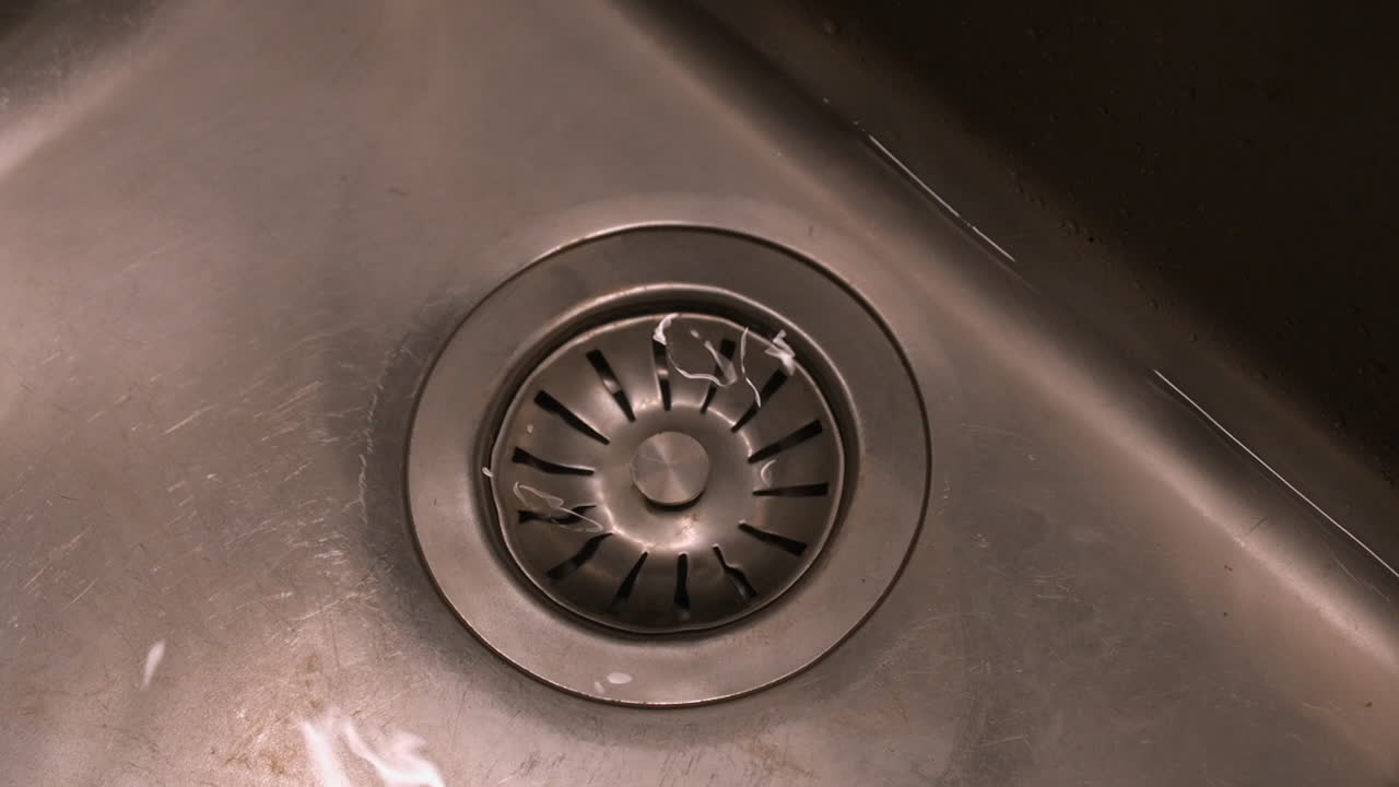 Water drains through stopper from stainless steel kitchen sink, detail