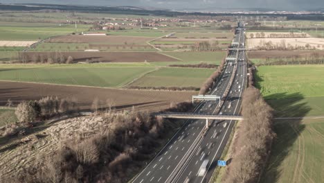 Timelapse-Aéreo-De-Drones-De-Una-Autopista-Alemana-Con-Luz-Solar-Brillante,-Molinos-De-Viento-Y-Automóviles