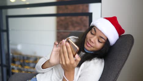 una adolescente usando un teléfono móvil en un sombrero de navidad