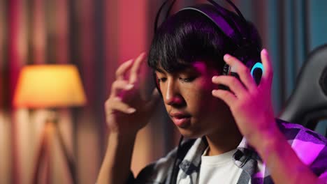 close up of asian teen boy gamer wearing head phones and start play video game on smartphone