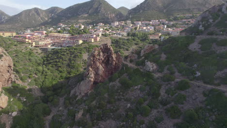 Aerial-view-travelling-out-over-the-city-of-Nebida-on-the-island-of-Sardinia-and-where-two-large-rock-formations-can-be-seen