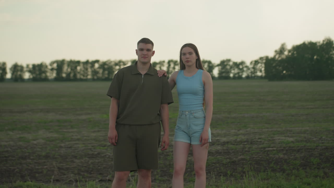 blurred passing car window view of couple walking along road side in rural field with woman hand on man shoulder at sunset under dramatic sky conveying motion connection and romance
