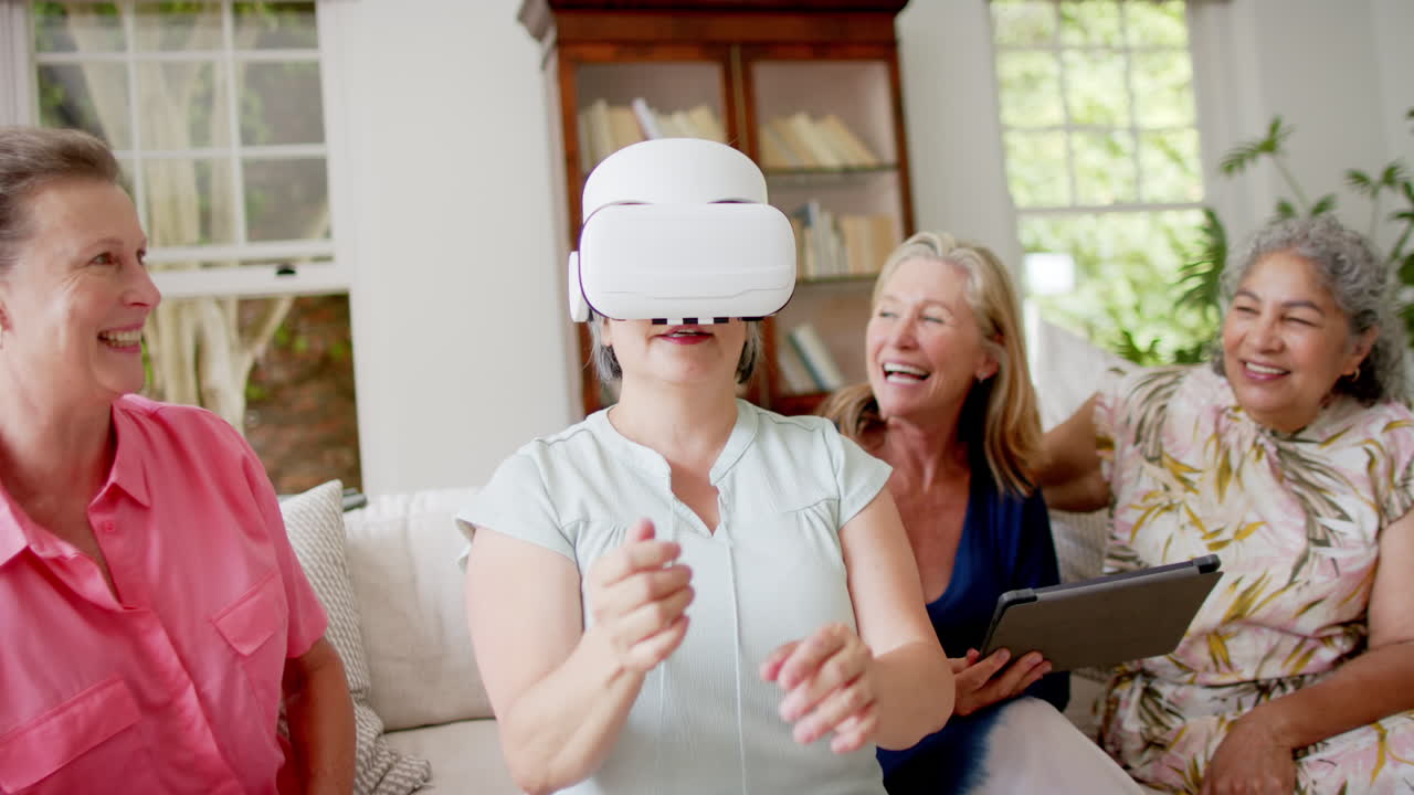 Gruppo eterogeneo di donne anziane si gode un'esperienza di realtà virtuale a casa.