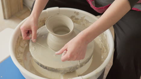 ceramics artist masterfully completes a vase on a potter's wheel, using wire to take it off