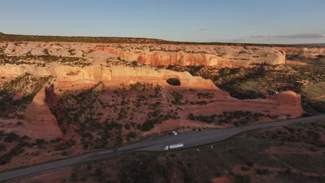 Aerial-perspective-of-Wilson-Arch-in-southeastern-Utah,-USA,-with-a-nearby-road-winding-through-the-landscape