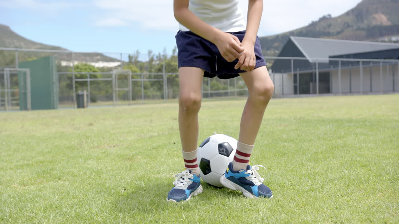 In school, child playing soccer on field, focusing on ball control