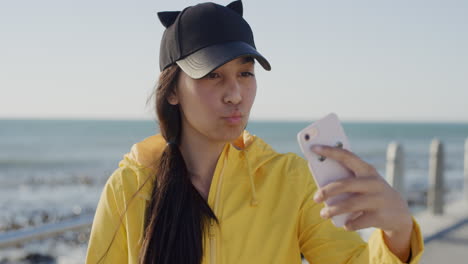Porträt-Eines-Hübschen-Teenager-Mädchens,-Das-Mit-Seinem-Smartphone-Posiert-Und-Ein-Selfie-Foto-Am-Wunderschönen-Sonnigen-Strand-Am-Meer-Macht-Und-Entspannte-Mobile-Kommunikation-Genießt