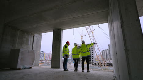 three civil engineers of development company are watching construction site rear view