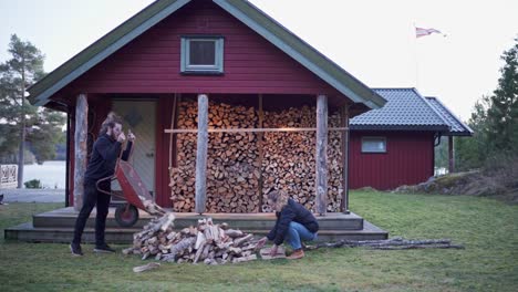 couple collecting firewoods in front of the red cabin