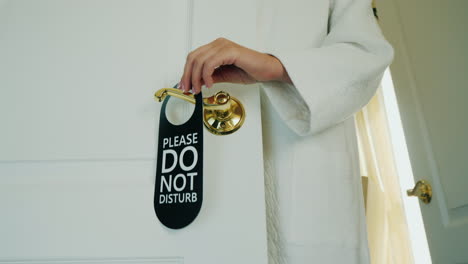 Unrecognizable-Woman-In-A-White-House-Coat-Hangs-A-Sign-On-The-Door-Do-Not-Disturb