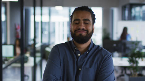 Portrait-of-mixed-race-businessman-standing-in-office-smiling-to-camera