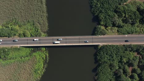 aerial view of motor vehicles driving across bridge road over river