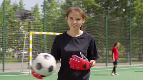 Junge-Fußballspielerin-Mit-Ball-Lächelt-Und-Blickt-Auf-Die-Kamera-Auf-Dem-Feld