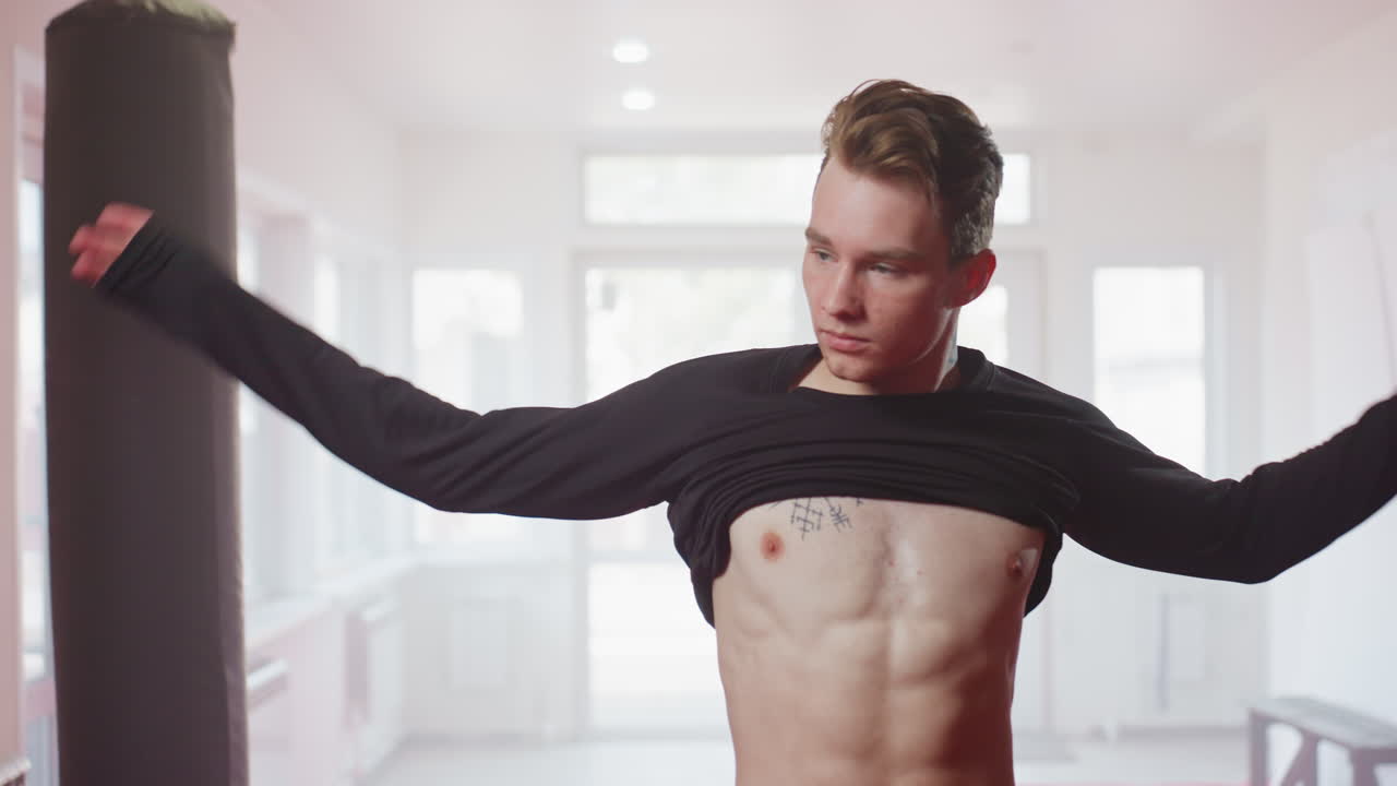 Soldier in gym environment wearing black shirt, showing muscular physique and serious expression, preparing for training session, representing discipline, strength, resilience, dedication