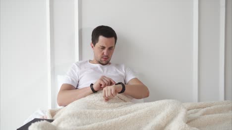 hombre comprobando la hora en su reloj inteligente en la cama