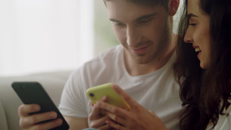 Happy-couple-using-mobile-phones-together-at-home.-Couple-looking-mobile-phones