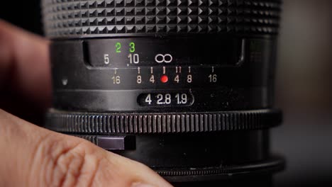 person focusing lens ring to infinity in a vintage camera