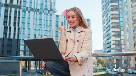 overjoyed happy mature businesswoman working on laptop screaming in delight on downtown city street