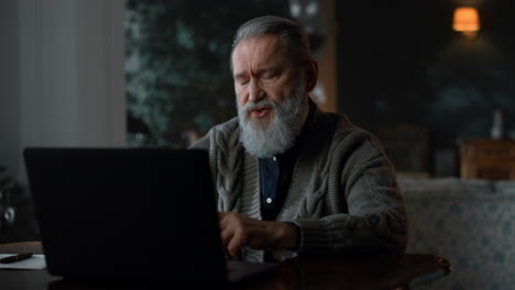 focused senior man talking during video call on laptop computer