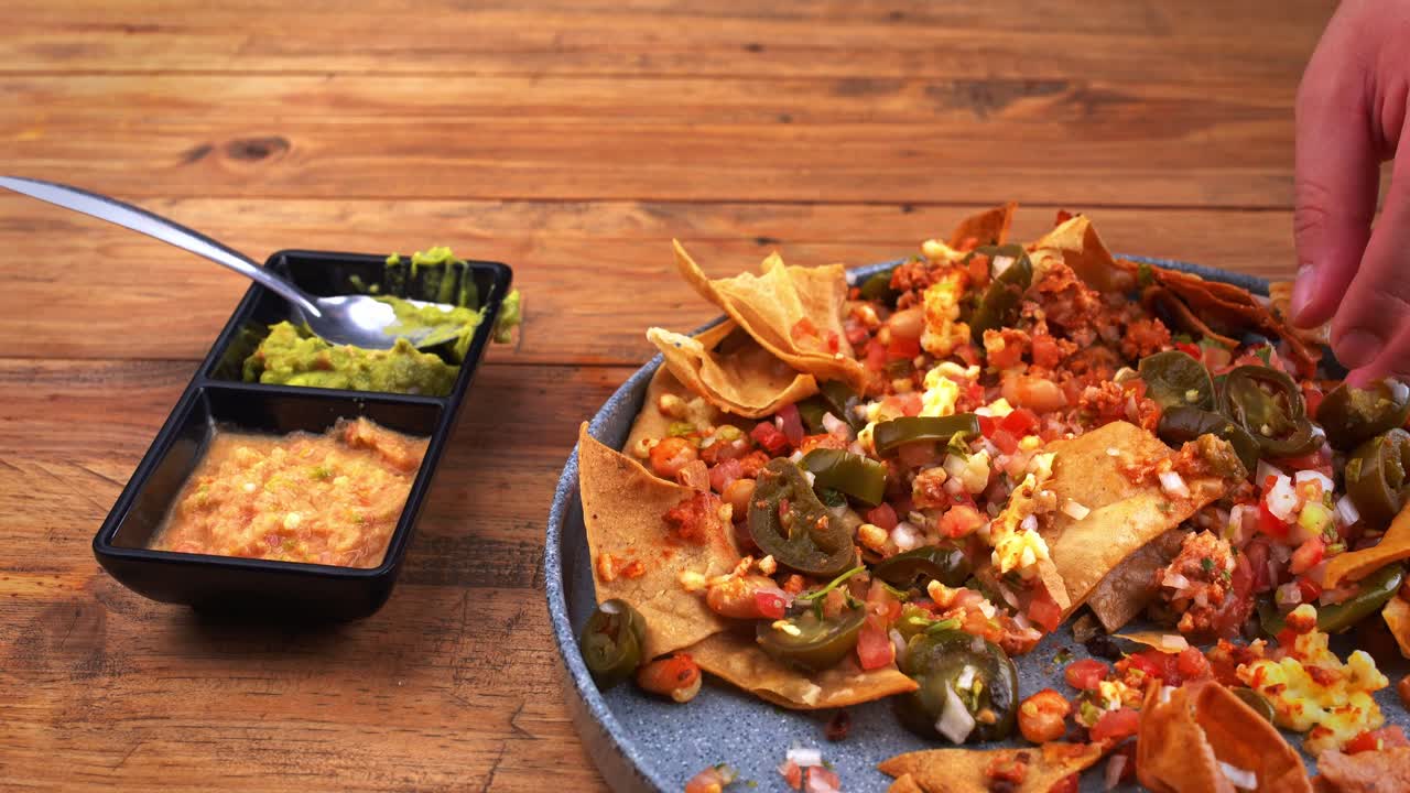 Up-close shot of a mouthwatering Mexican-style nacho dish topped with zesty pico de gallo salsa, served alongside a generous portion of homemade guacamole