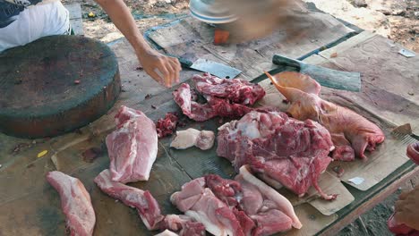 medium shot of a girl butchering a pig on a small market stall by the side of the street