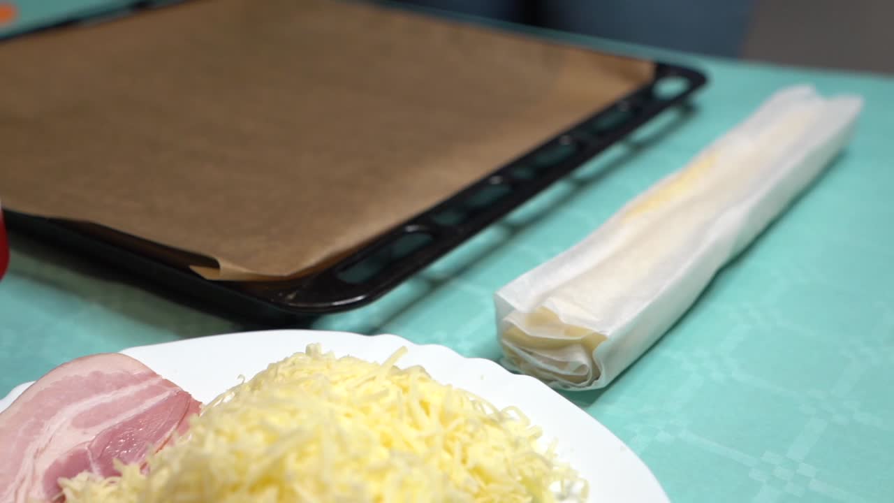 재료와 함께 청록색 테이블에 피자 반죽 롤을 배치하는 여자