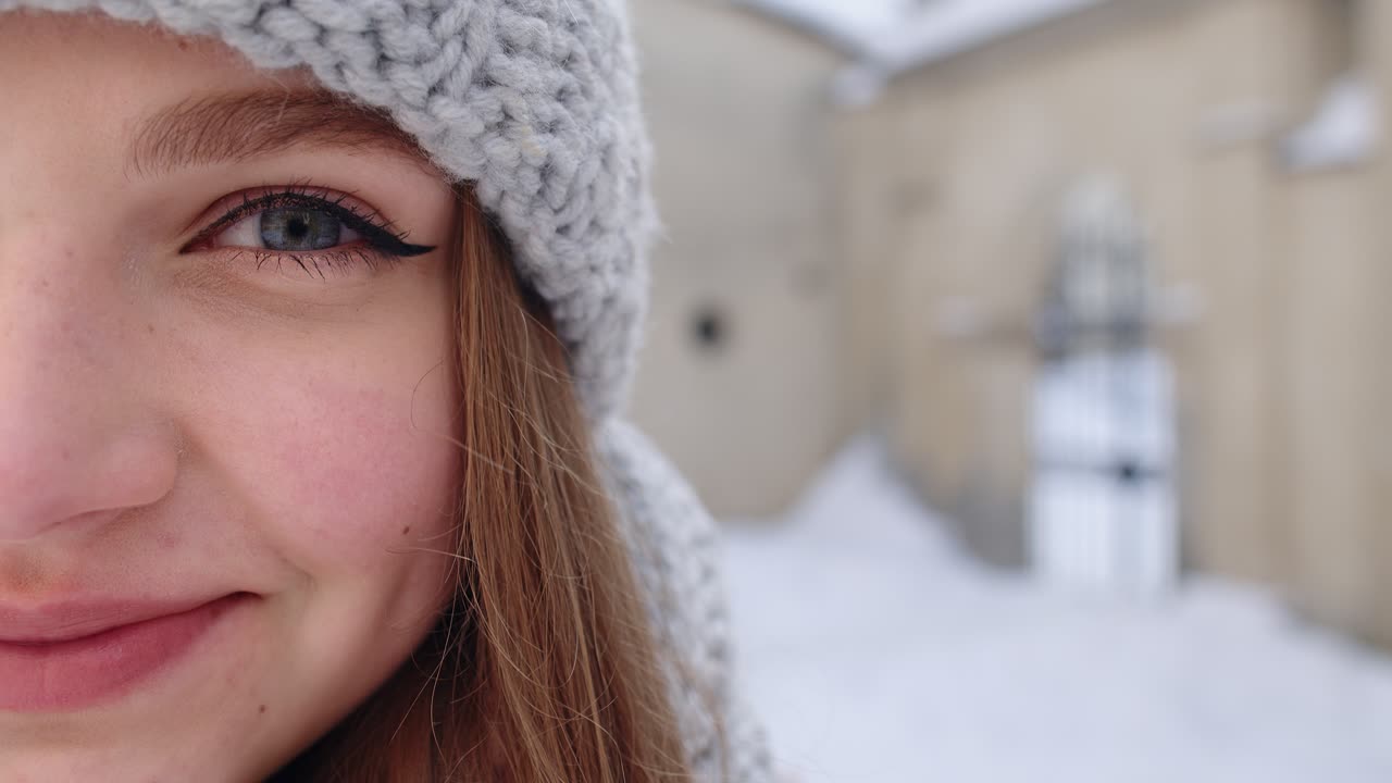 retrato de una chica caucásica bastante feliz con una sonrisa en la cara posando en el fondo de la calle de la ciudad de invierno