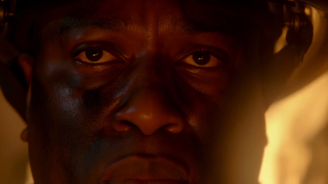 Black Firefighter Closeup Facing Flames, Helmeted Portrait With Sootstreaked Skin And Intense Eyes, Ember Glow