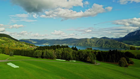 pristine mountain lake valley with green fields, blue sky and forests