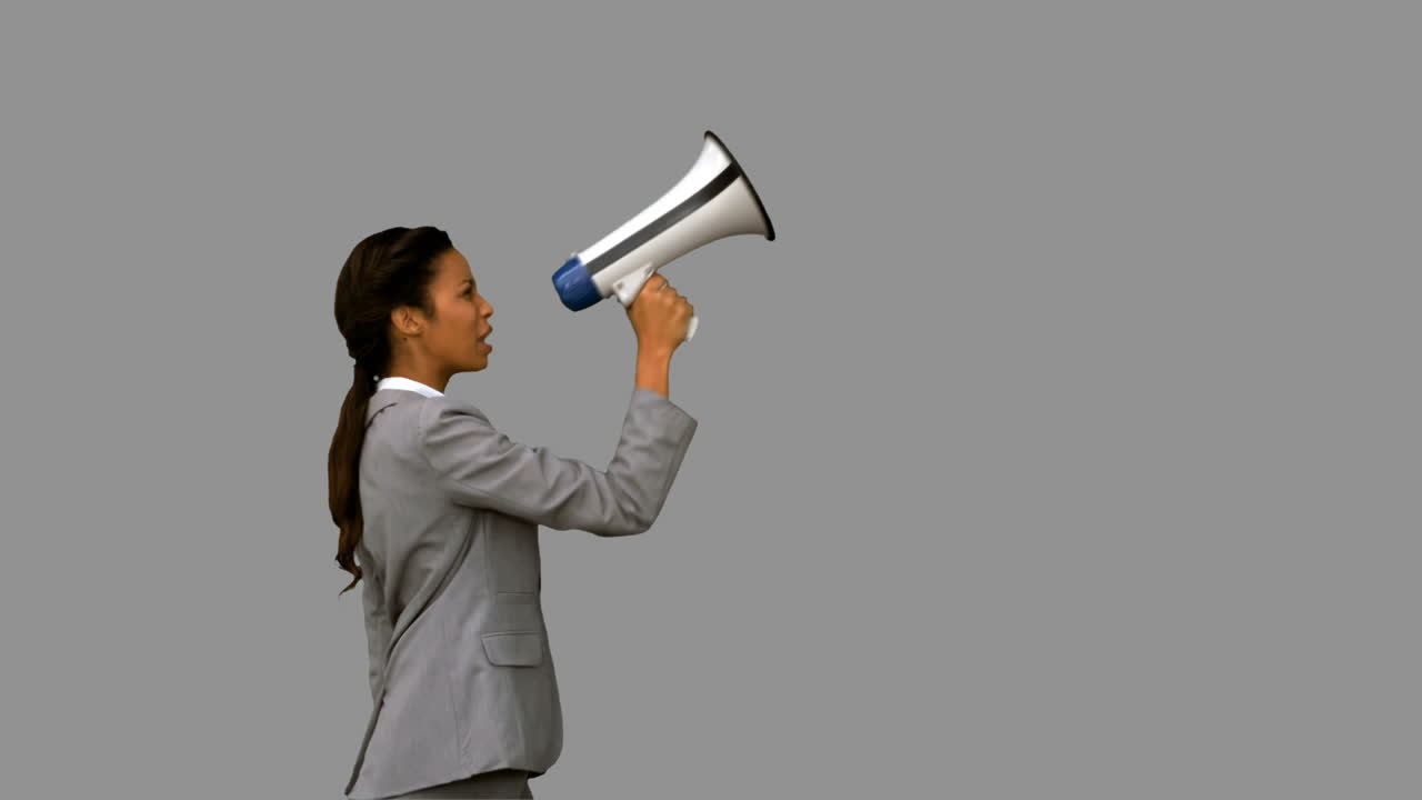 Businesswoman shouting into a megaphone on grey screen