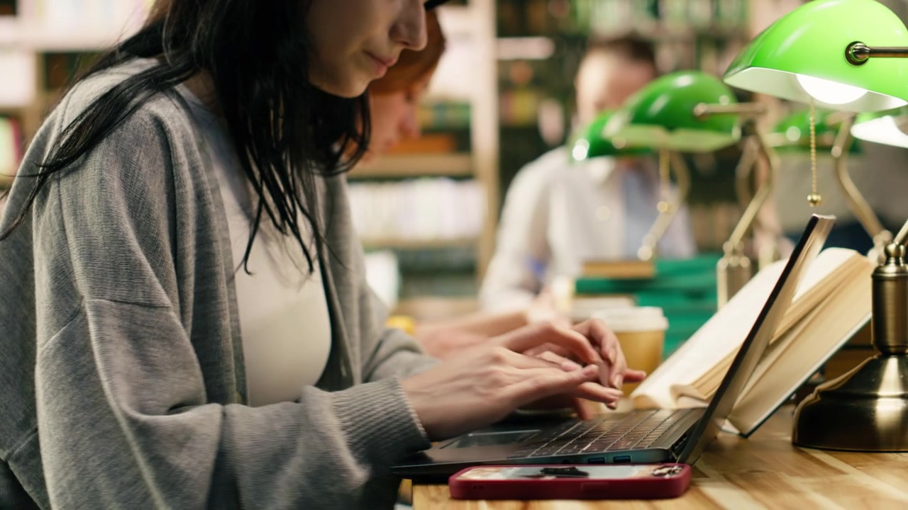 Young adult student distracted by mobile phone notification while using laptop