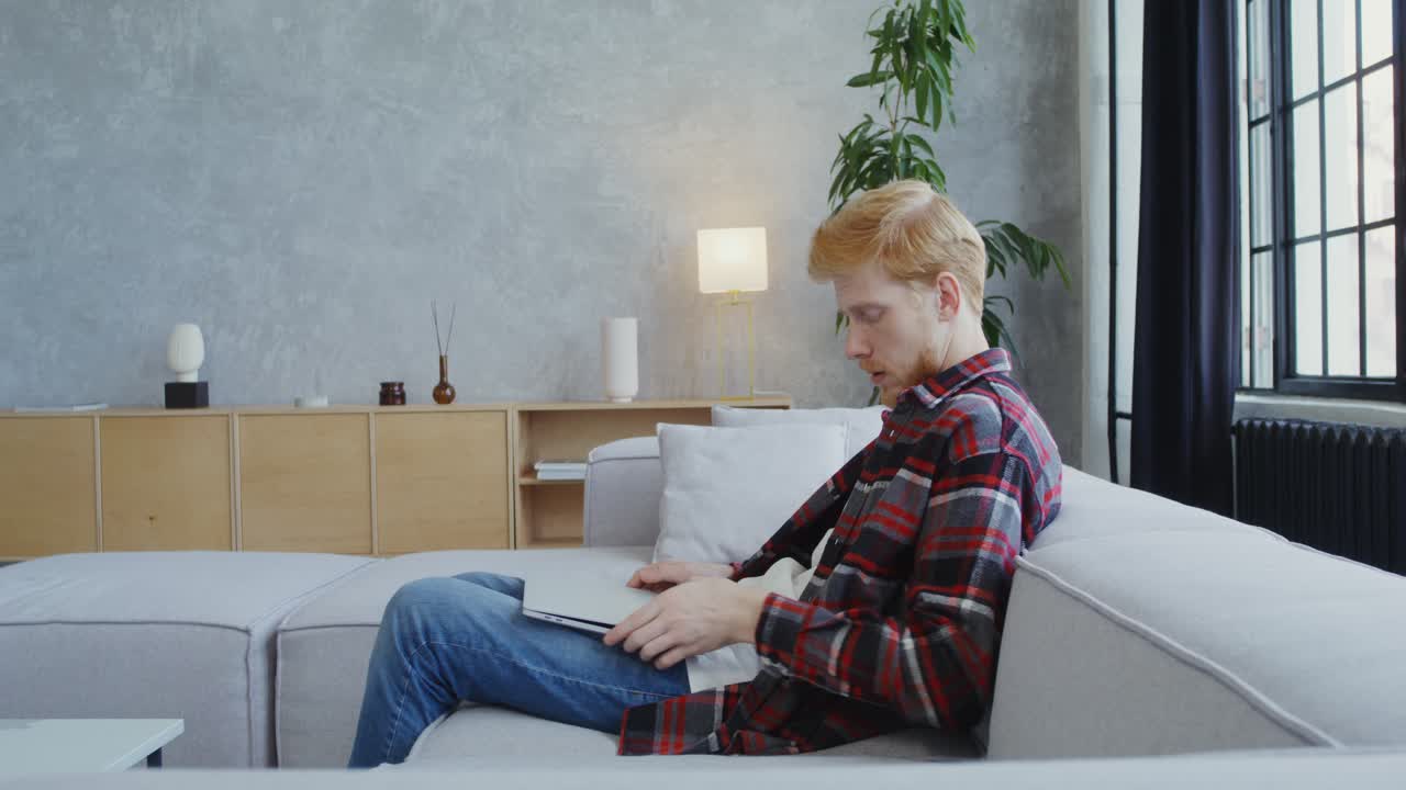 hombre trabajando en una computadora portátil en una sala de estar moderna