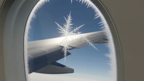 frosty airplane window view with wing and sun