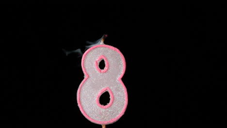 Eight-birthday-candle-flickering-and-extinguishing-on-black-background