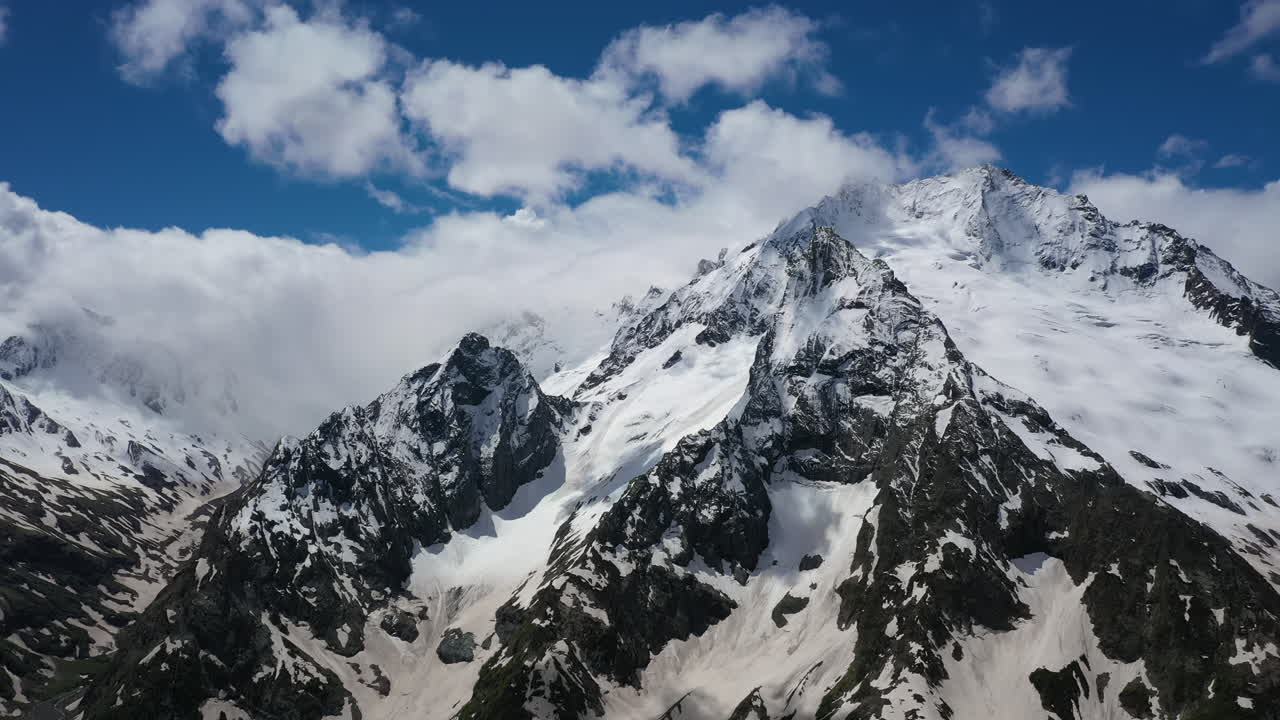 눈 덮인 아름다운 산봉우리와 빙하 위로 산 구름을 통과하는 항공 비행.