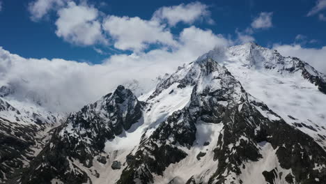 vuelo aéreo a través de nubes montañosas sobre hermosos picos nevados de montañas y glaciares.
