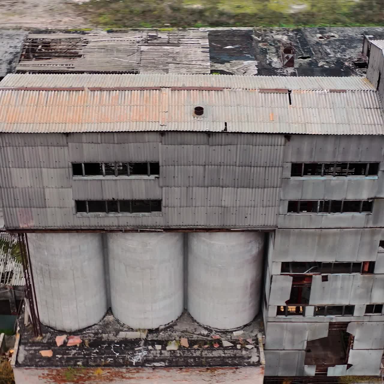 Ruined factory with damaged roof. Abandoned buildings on the field of military actions. Destroyed architecture. Aerial view.
