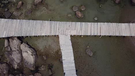 wooden boardwalk on rocky beach connecting sea with the beach