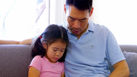 Father-and-daughter-using-digital-tablet-in-living-room