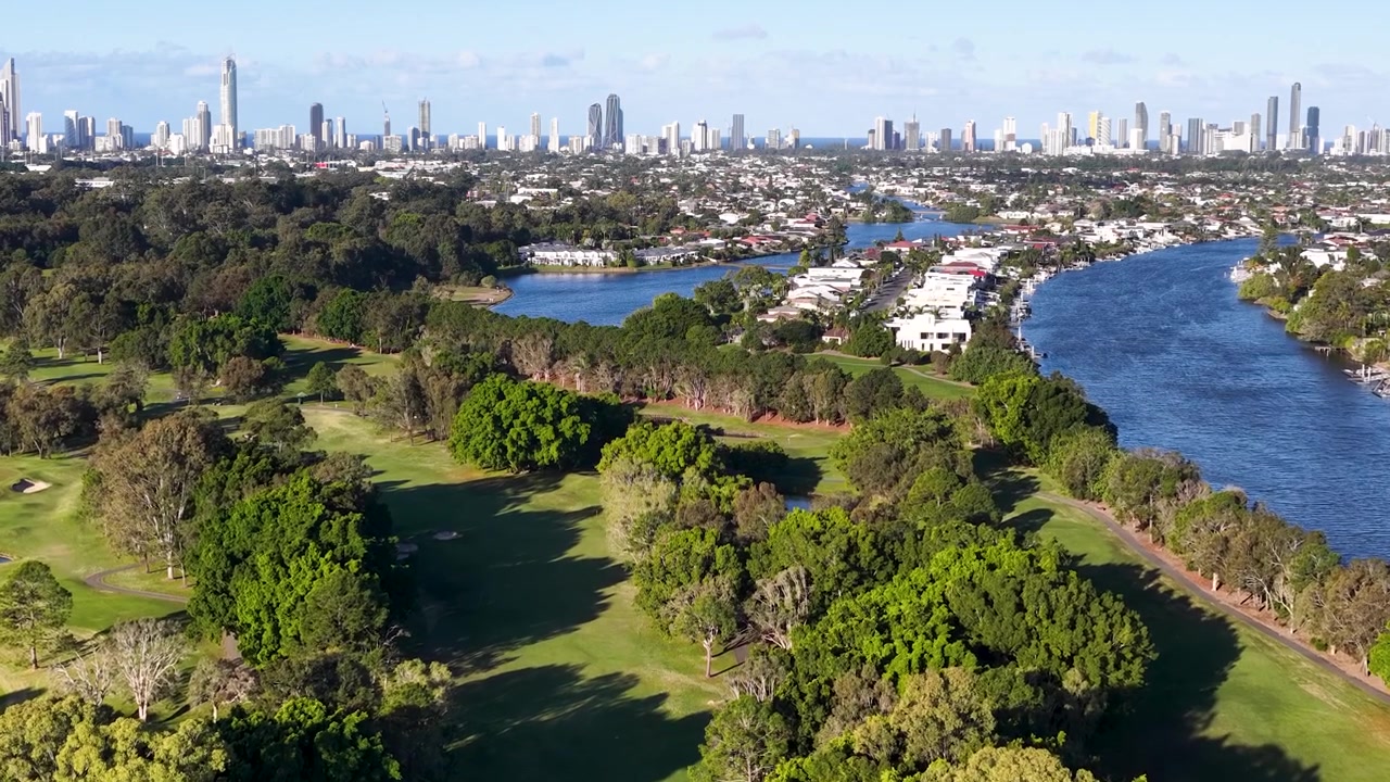 Veduta aerea di un campo da golf e di un fiume con lo skyline della città.