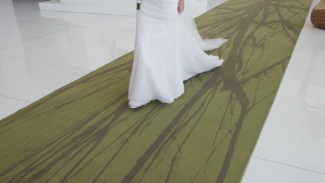 bride gently lifts her lace dress, revealing her shoes, on a patterned green and beige floor in lisbon