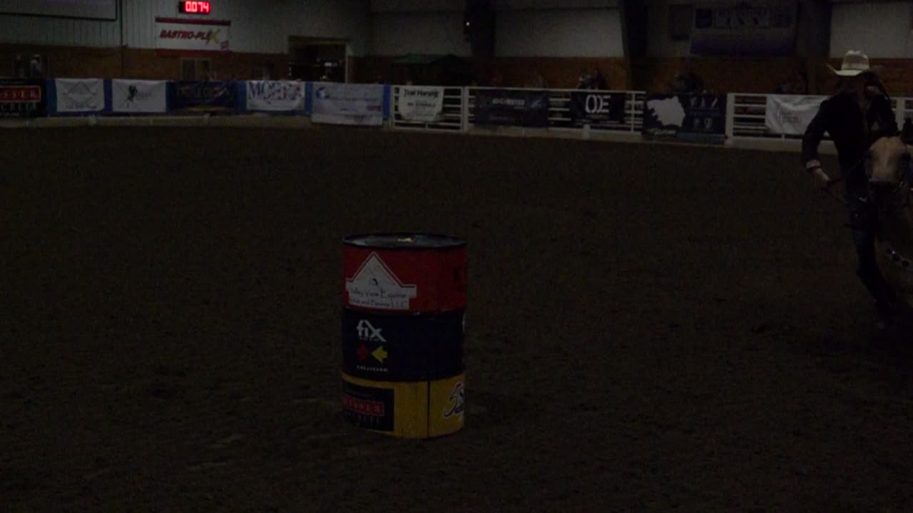 Cavaliere e cavallo in competizione in una corsa a barili in un'arena al coperto